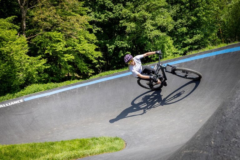 Dynamik auf dem Pumptrack – Fahrtechnik und Spaß bei den Burgenland Trails Mountainbiker in Action auf dem asphaltierten Pumptrack der Burgenland Trails bei Sonnenschein.