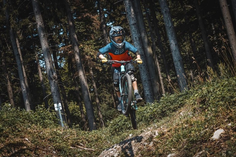 Adrenalin pur auf den Burgenland Trails – Fahrspaß am Geschriebenstein Mountainbiker springt auf einem Trail im Wald der Burgenland Trails in voller Ausrüstung über eine Erhebung.