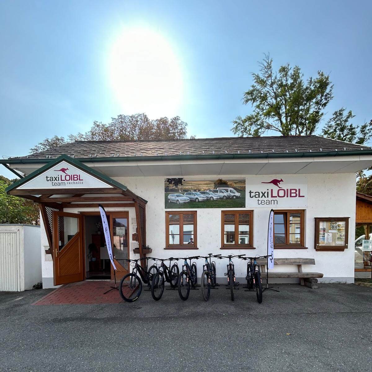 Eingangsbereich vom Taxi Loibl Team in Rechnitz, mit mehreren Mountainbikes zur Miete vor dem Gebäude – zeigt die zentrale Anlaufstelle für Verleih, Shuttle-Service und Beratung.